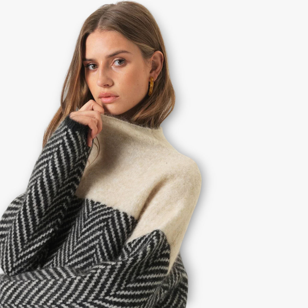 Woman wearing a black and beige sweater with a plain background